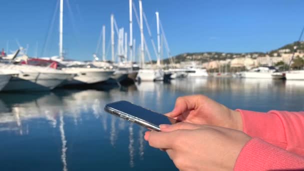 Menina Camisola Rosa Contra Iates Fundo Segurando Smartphone Mensagens Texto — Vídeo de Stock