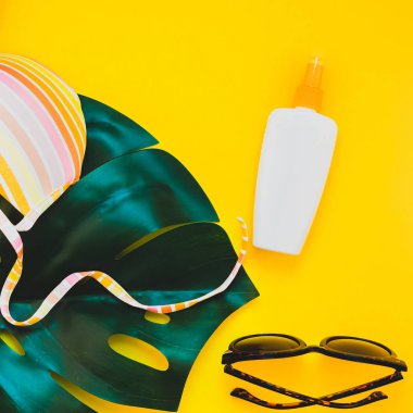 Tropikal orman palm monstera bırakır, güneş gözlüğü, Güneş kremi boş şişe mockup ve kadının mayo üstüne parlak kare Kağıt arka plan sarı. Yaz tatil yaratıcı düz yatıyordu kavramı şablonu