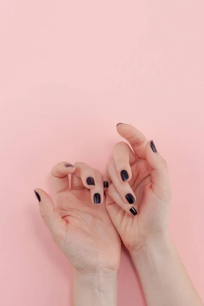 Stylish trendy female black manicure. Beautiful young woman\'s hands on millennial pink pastel background. Beauty and SPA concept. Template for feminine blog social media