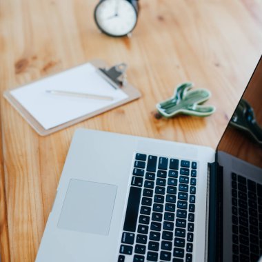 Rahat çalışma yerde ahşap masa ve modern dizüstü üzerinde döşeme ev ofis. Serbest iş kare kavramı