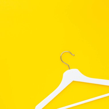 Yaratıcı en iyi görünüm düz yatıyordu Beyaz ahşap askı izole kalın sarı arka plan kopya alan minimalizm tarzı ile. Şablon moda kadınsı blog sosyal medya satış mağaza promosyon tasarım alışveriş konsepti