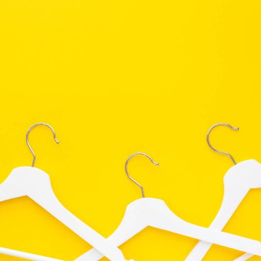 Yaratıcı en iyi görünüm düz yatıyordu Beyaz ahşap askı izole kalın sarı arka plan kopya alan minimalizm tarzı ile. Şablon moda kadınsı blog sosyal medya satış mağaza promosyon tasarım alışveriş konsepti
