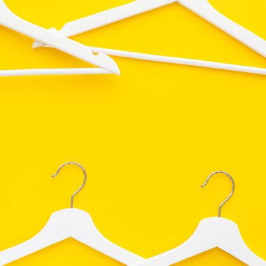 Yaratıcı en iyi görünüm düz yatıyordu Beyaz ahşap askı izole kalın sarı arka plan kopya alan minimalizm tarzı ile. Şablon moda kadınsı blog sosyal medya satış mağaza promosyon tasarım alışveriş konsepti