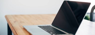 Rahat çalışma yerde ahşap masa ve modern dizüstü üzerinde döşeme ev ofis. Serbest çalışma kavramı. Uzun geniş afiş