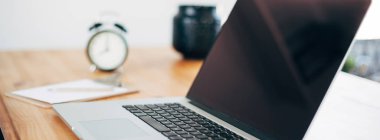 Rahat çalışma yerde ahşap masa ve modern dizüstü üzerinde döşeme ev ofis. Serbest çalışma kavramı. Uzun geniş afiş
