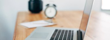 Rahat çalışma yerde ahşap masa ve modern dizüstü üzerinde döşeme ev ofis. Serbest çalışma kavramı. Uzun geniş afiş