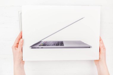 Berlin, Almanya - 09 Aralık 2018: en son Apple Macbook Pro dizüstü bilgisayar kutusu beyaz ahşap arka plan karşı holding kadın eller. Unboxing üstten görünüm kavramı kopya alanı ile