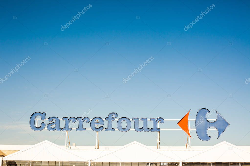 SAGUNTO, SPAIN - FEBRUARY 08, 2019: Carrefour supermarket chain brand logo at its building located in Sagunto shopping area, Spain. Clear bright blue sky