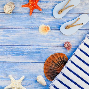 Yaratıcı düz kavramı yaz seyahat tatil yatıyordu. Kabukları ve deniz yıldızı kopya alanı rustik tarzı kare çerçeve şablonu metin pastel mavi ahşap plakalar zemin üzerine üstten görünüm havlu Flip floplar