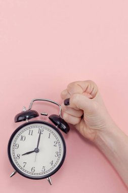 Yaratıcı düz sabah zaman duygular kavramı en iyi siyah vintage çalar saat pastel bin yıllık pembe renkli kağıt arka plan metin için kopya alanı en az stil şablonu ile birlikte tutan kadın el görünümünü yatıyordu.