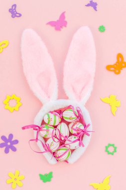 Yaratıcı Top View düzlük tatil kompozisyonu. Paskalya yumurtaları tavşan kulakları. Pembe kağıt arka plan üzerinde bahar çiçekleri.