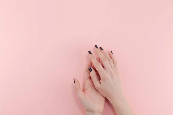 Stylish trendy female black manicure. Beautiful young woman's hands on millennial pink pastel background. Beauty and SPA concept. Template for feminine blog social media