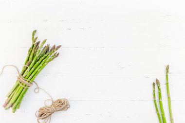 Beyaz ahşap arka planda taze yeşil kuşkonmaz.