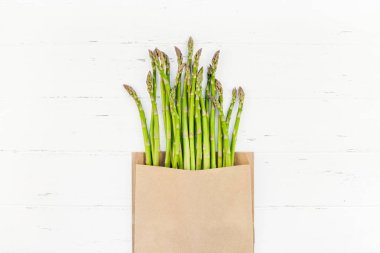 Beyaz ahşap arka planda taze yeşil kuşkonmaz.