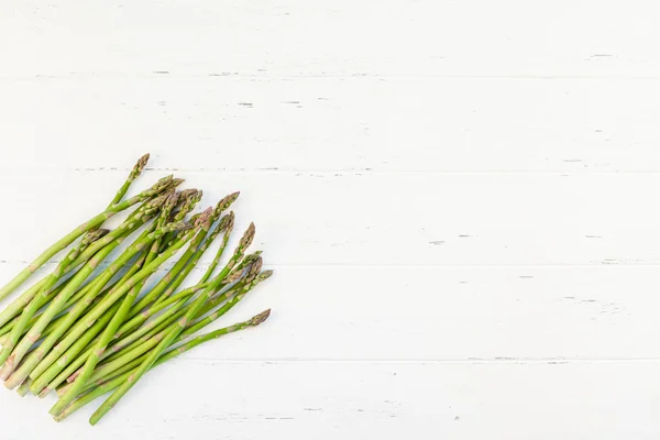 Verse groene asperges op witte houten ondergrond — Stockfoto