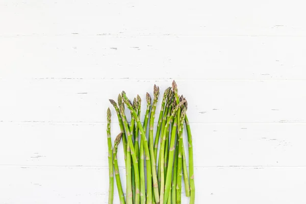 Verse groene asperges op witte houten ondergrond — Stockfoto