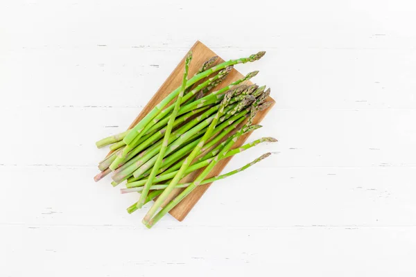 Asparagi verdi freschi su sfondo bianco in legno — Foto Stock