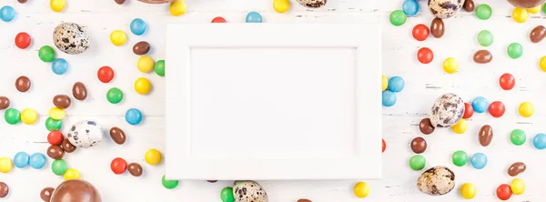 Easter frame with chocolate eggs, colorful candies