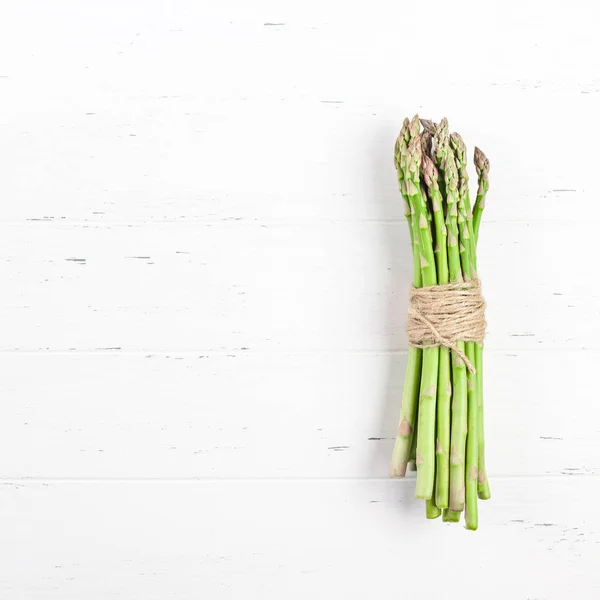 Verse groene asperges op witte houten ondergrond — Stockfoto