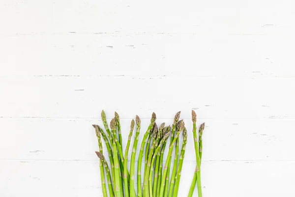 Verse groene asperges op witte houten ondergrond — Stockfoto