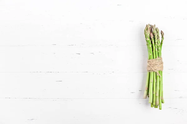 Verse groene asperges op witte houten ondergrond — Stockfoto