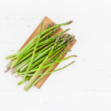 Beyaz ahşap arka planda taze yeşil kuşkonmaz.