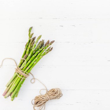 Beyaz ahşap arka planda taze yeşil kuşkonmaz.