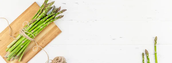 Asparagi verdi freschi su sfondo bianco in legno — Foto Stock