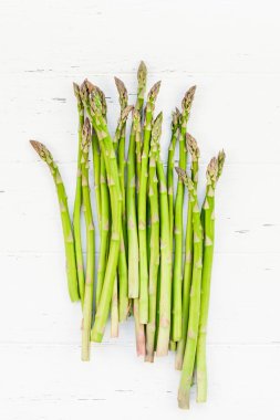 Beyaz ahşap arka planda taze yeşil kuşkonmaz.