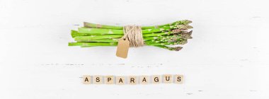 Beyaz ahşap arka planda taze yeşil kuşkonmaz.