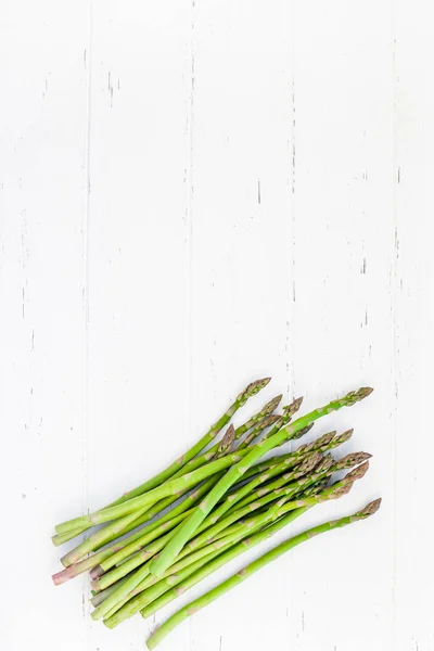 Verse groene asperges op witte houten ondergrond — Stockfoto