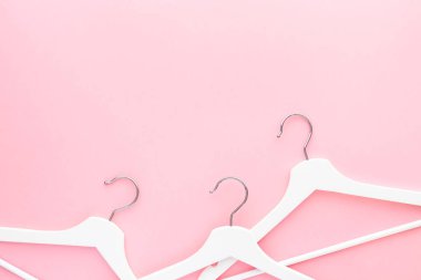 Pastel pembe arka planda beyaz askılar