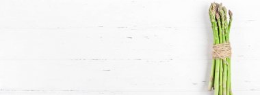 Beyaz ahşap arka planda taze yeşil kuşkonmaz.