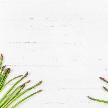 Beyaz ahşap arka planda taze yeşil kuşkonmaz.