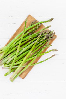 Beyaz ahşap arka planda taze yeşil kuşkonmaz.