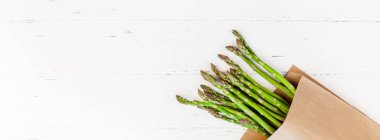 Beyaz ahşap arka planda taze yeşil kuşkonmaz.