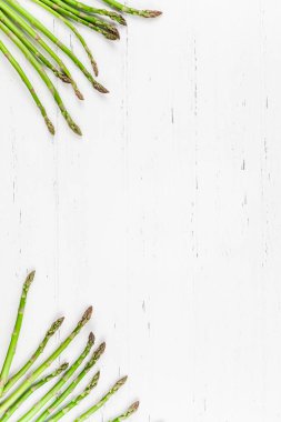 Beyaz ahşap arka planda taze yeşil kuşkonmaz.