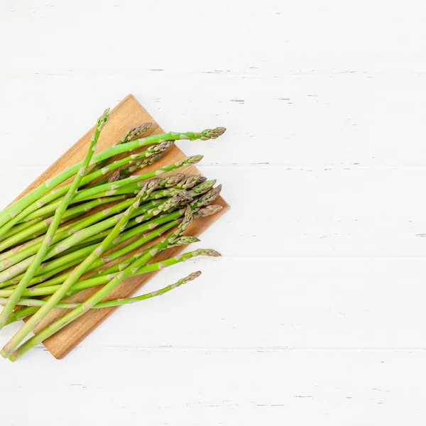 Verse groene asperges op witte houten ondergrond — Stockfoto