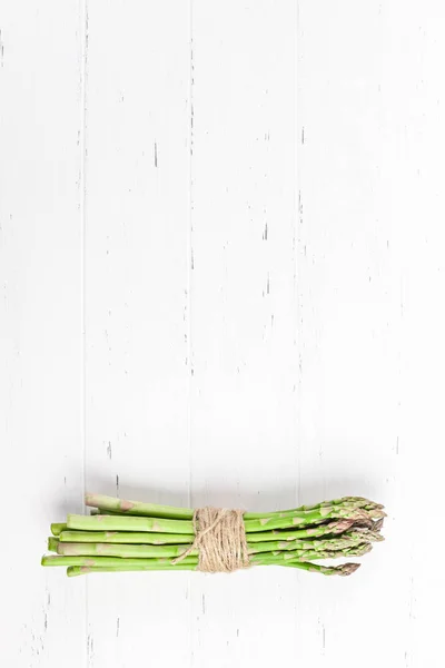 Verse groene asperges op witte houten ondergrond — Stockfoto