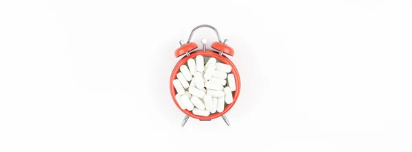 Будильник с белыми таблетками — стоковое фото