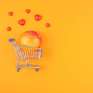 Turuncu arka planda alışveriş sepetinde Mango meyve