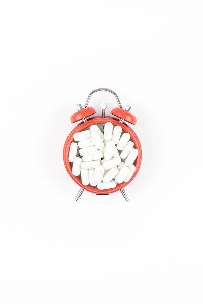 Будильник с белыми таблетками — стоковое фото