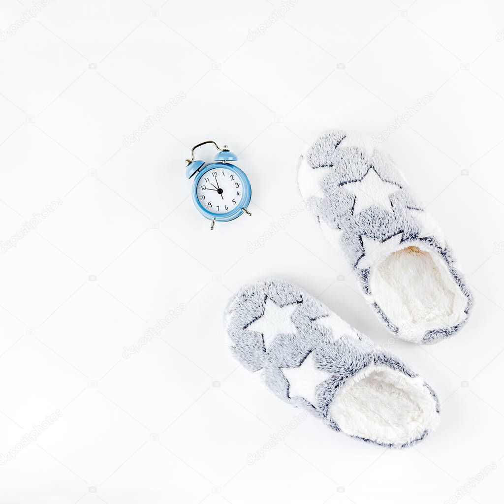 Soft fluffy slippers and blue alarm clock