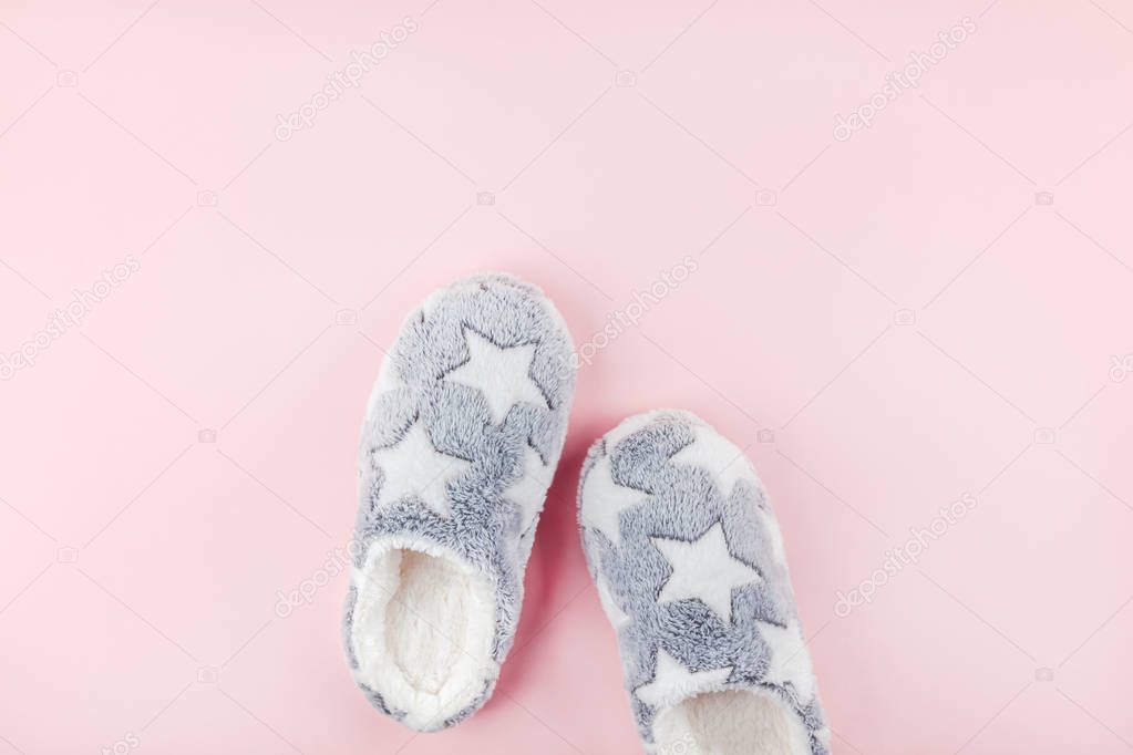 Soft fluffy slippers on pink background