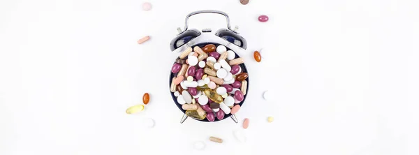 Будильник с цветными таблетками — стоковое фото