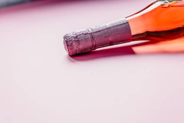 Pembe arka planda gül şampanya şarap şişesi