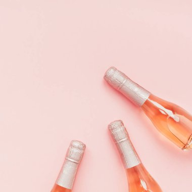 Pembe arka planda gül şampanya şarap şişesi