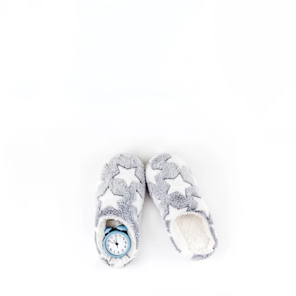 Soft fluffy slippers and blue alarm clock — Stock Photo, Image