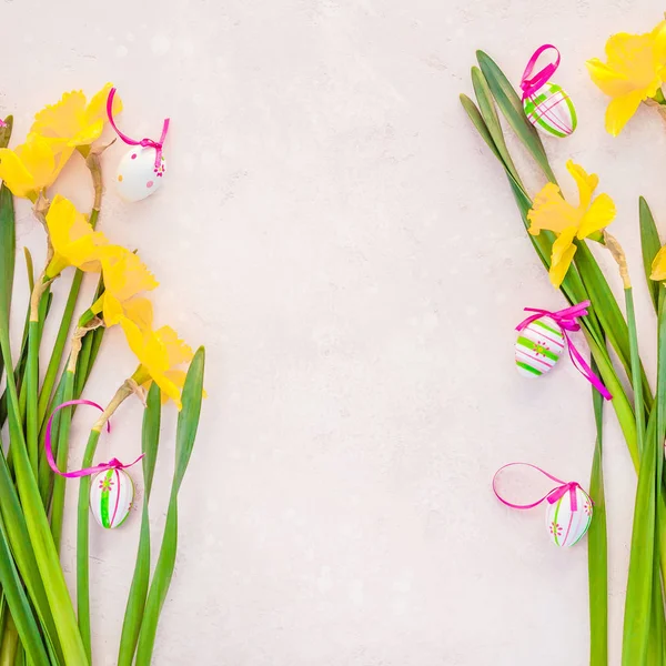 Gelbe Narzissen und Ostereier auf rosa Hintergrund — Stockfoto