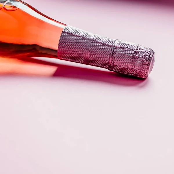 Üveg rózsás pezsgőbor rózsaszín háttérrel — Stock Fotó
